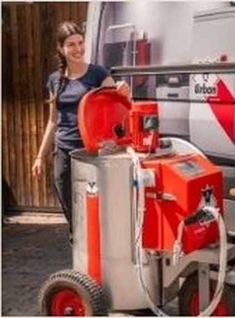 Mitarbeiterin mit fahrbarem Tränkemixer vor dem Stall